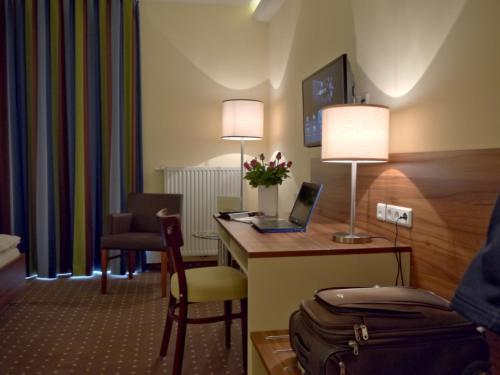 a hotel room with a desk with a laptop on it at Hotel Friesische Wehde in Bockhorn