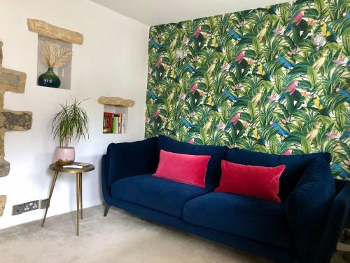 a blue couch with two red pillows in a living room at The Old Studio in Knaresborough