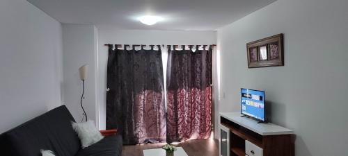 Sala de estar con ventana, sofá y TV en Departamento céntrico en Tigre II en Tigre