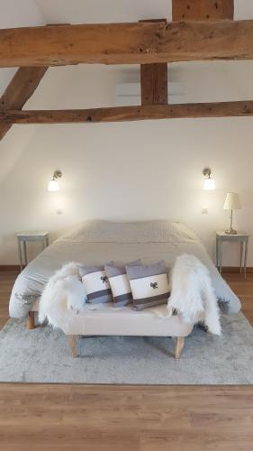 - une chambre dotée d'un lit avec des plumes et des oreillers blancs dans l'établissement Manoir de Pierreville, à Audouville-la-Hubert