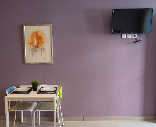 ein Esszimmer mit einem Tisch und einem TV an einer lila Wand in der Unterkunft @LAKE STUDIO in Ioannina