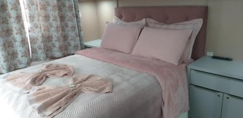 um quarto com uma cama com um cobertor e almofadas cor-de-rosa em Casa de Temporada Familiar em Urubici