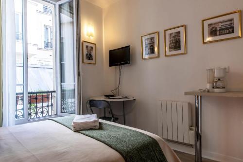 1 dormitorio con 1 cama, TV y ventana en Montmartre Apartments Chagall, en París