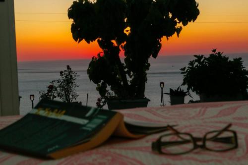 a pair of glasses sitting on a table in front of a sunset at Sette Isole Countryside Retreat Near Egremni Beach in Athanion