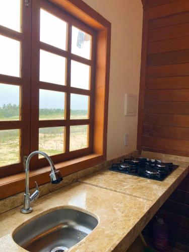 a kitchen with a sink and a stove and a window at Chalé Bela Vista in Tatajuba