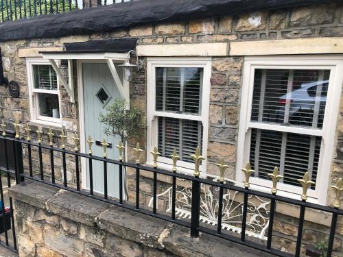 a stone house with a black fence and two windows at The Old Studio in Knaresborough