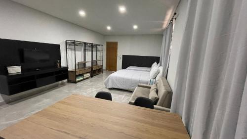 a bedroom with a bed and a couch and a table at Novo apartamento Studio a poucos passos do Paraguai - Vila Portes in Foz do Iguaçu