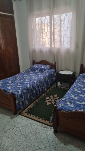 um quarto com duas camas e um tabuleiro de xadrez no chão em appartement centre kenitra em Kenitra