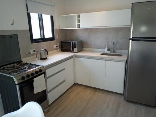 a kitchen with white cabinets and a stainless steel refrigerator at Maderos Apart in Federación