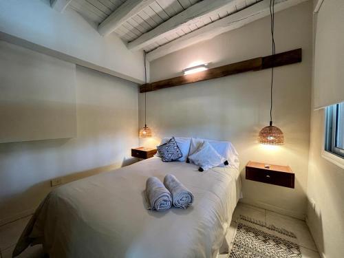 1 dormitorio con 1 cama blanca grande y 2 almohadas en La Posadita de Chacras en Chacras de Coria