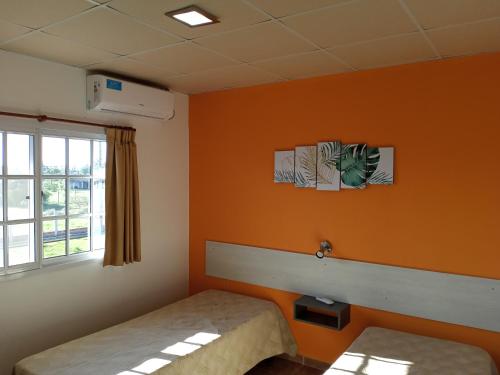 a room with orange walls and a bed and a window at Las Casuarinas in Federación