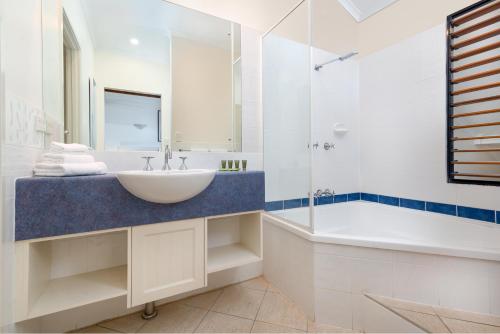 a white bathroom with a sink and a tub and a sink at Seascape Holidays at 30 Tropic Style in Port Douglas