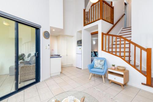 a living room with a staircase and a blue chair at Seascape Holidays at 30 Tropic Style in Port Douglas