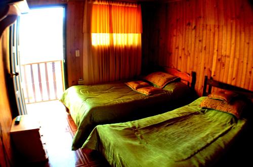 two beds in a room with a window at Cabana hotel eco turistico el EDEN in Güicán
