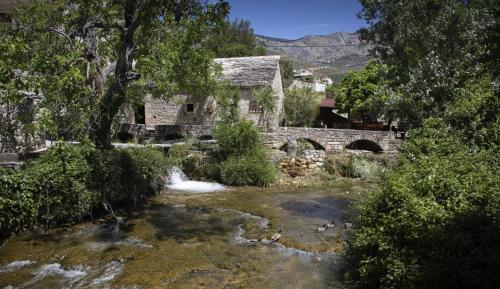 an old stone house with a river and a bridge at RELAX apartment Split area with private jacuzzi on terrace with mountain view in Srinjine