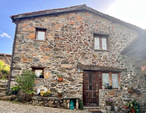 an old stone house with flowers in front of it at Casa da Barriada I in Bragança