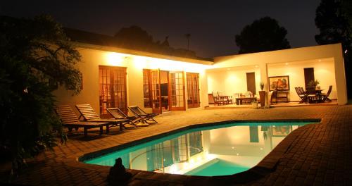 a house with a swimming pool at night at Fynbos Guest House Riversdale in Riversdale