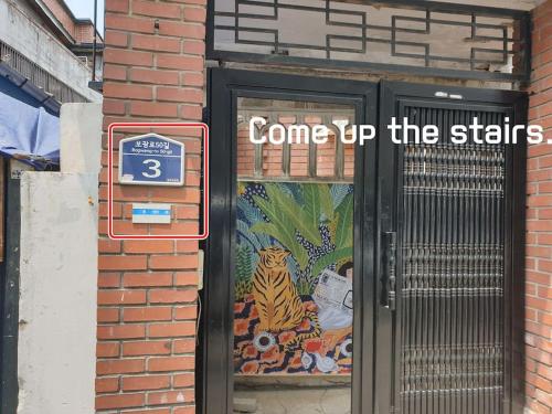a door with a sign that says come up the stairs at House Mongja in Seoul