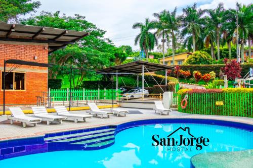 a swimming pool with lounge chairs and an umbrella at Hostal San Jorge in Pereira