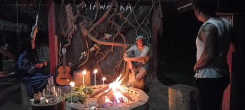Un uomo in piedi davanti a un tavolo con un fuoco di Ayawaska Atractivo Sacha Wasi a Nueva Loja