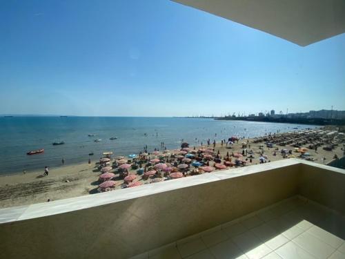 a beach with umbrellas and people on the beach at Hotel Tirona in Durrës