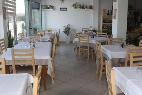 a restaurant with tables and chairs with white tablecloths at Hotel Tirona in Durrës
