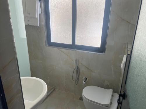 a bathroom with a toilet and a sink and a window at Hotel Tirona in Durrës