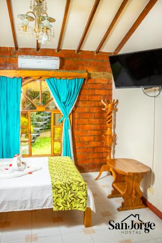 a bedroom with a bed and a window and a tv at Hostal San Jorge in Pereira