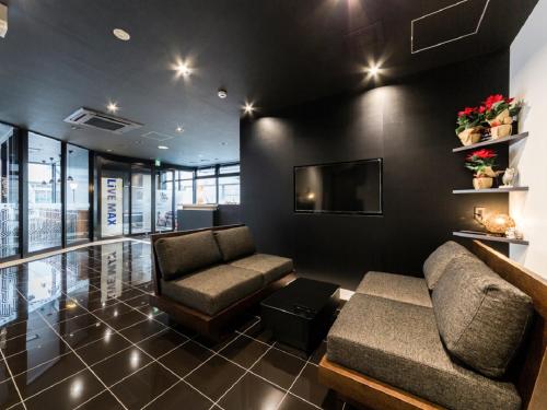 a living room with a couch and a tv at HOTEL LiVEMAX Kakegawa-Ekimae in Kakegawa