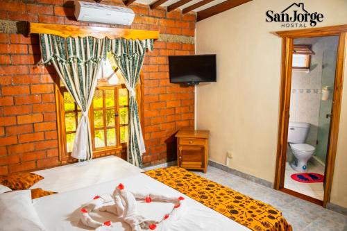 a bedroom with a bed and a window and a tv at Hostal San Jorge in Pereira