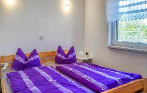 a bedroom with purple pillows on a bed with a window at Nice Home In Behrenhoff With Kitchen in Behrenhoff