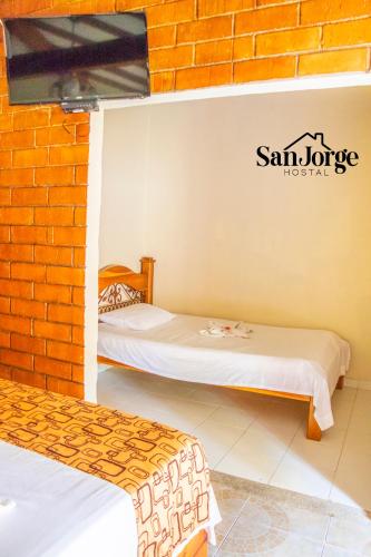 two beds in a room with a brick wall at Hostal San Jorge in Pereira
