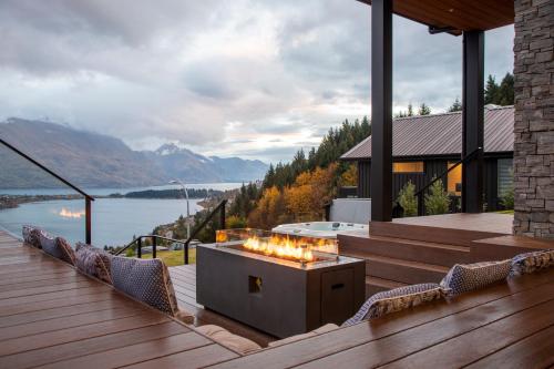 a deck with a fire pit with a view of a lake at Aroha on Florence by Sothebys Luxury Rental Homes in Queenstown