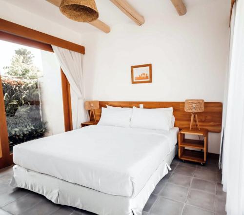 um quarto com uma grande cama branca e uma janela em Canggu Village Accommodation em Canggu