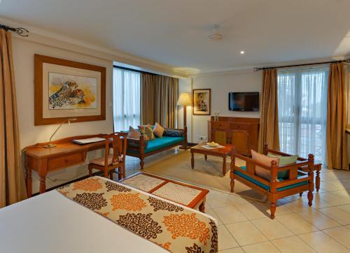 Habitación de hotel con dormitorio y sala de estar. en The Heron By Sarovar Portico India, en Nairobi