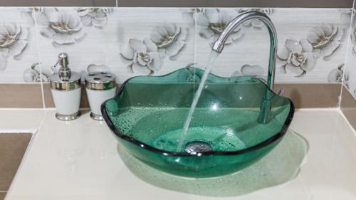 ein Waschbecken mit einer grünen Glasschüssel mit einem Wasserhahn in der Unterkunft Bangtao Guest House in Strand Bang Tao