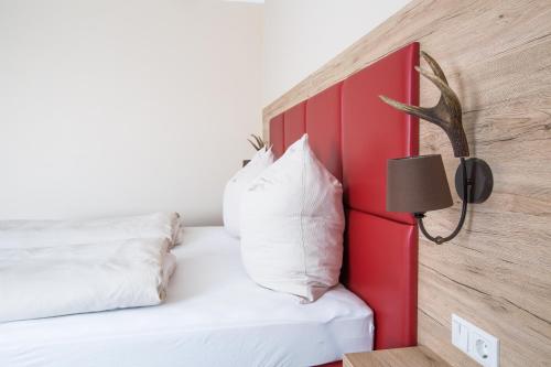 um quarto com uma cama com uma cabeceira vermelha e um candeeiro em Aparthotel Altomünster - Garni em Altomünster