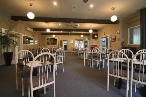 West Coaster Motel في كوينزتاون: غرفة طعام مع طاولات وكراسي بيضاء