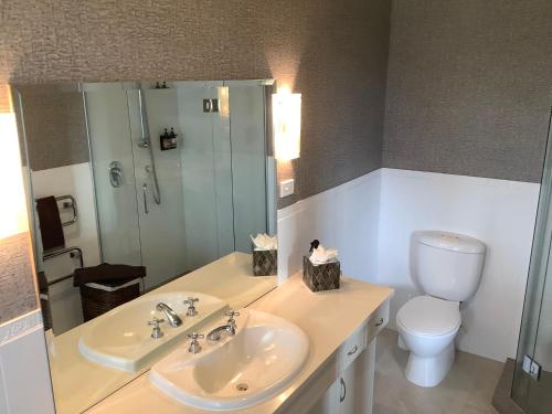 a bathroom with two sinks and a toilet and a mirror at KARANDA BnB in Rotorua