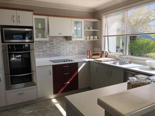 uma cozinha com armários brancos e uma grande janela em KARANDA BnB em Rotorua