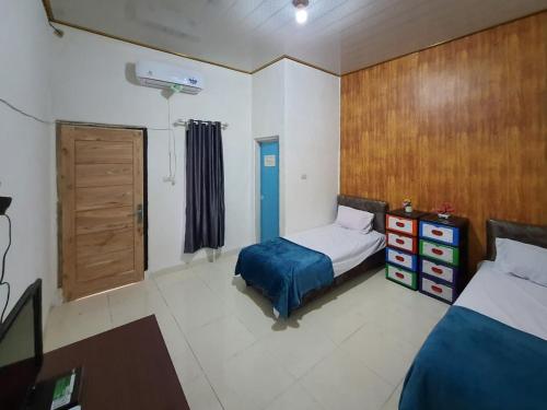 a bedroom with two beds and a wooden door at RedDoorz Syariah at Labuhan Maringgai Lampung in Mataram-baru