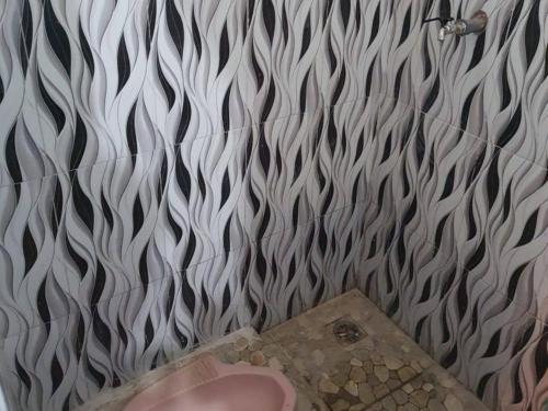 a bathroom with a white and black patterned wall at RedDoorz Syariah at Labuhan Maringgai Lampung in Mataram-baru