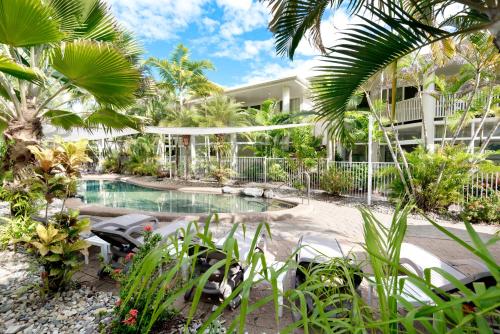 um resort com piscina e palmeiras em Tropical Nites Holiday Townhouses em Port Douglas