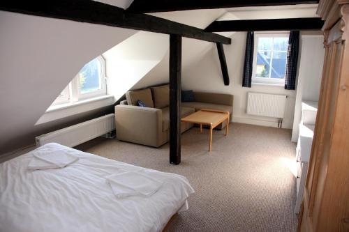 a bedroom with a bed and a couch and windows at Penzion Pod lesem in Pec pod Sněžkou