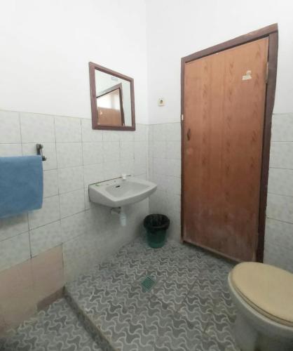 a bathroom with a toilet and a sink and a door at Sentosa Hotel & Restaurant Bekasi in Bekasi
