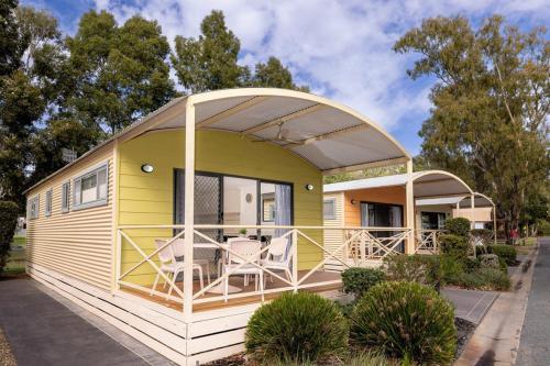 une petite maison jaune et blanche avec une terrasse couverte dans l'établissement BIG4 Deniliquin Holiday Park, à Deniliquin