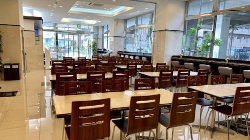 Toyoko Inn Tokyo Fuchu Nambu sen Minami tama Ekimae في Inagi: غرفة مع طاولات وكراسي في مبنى