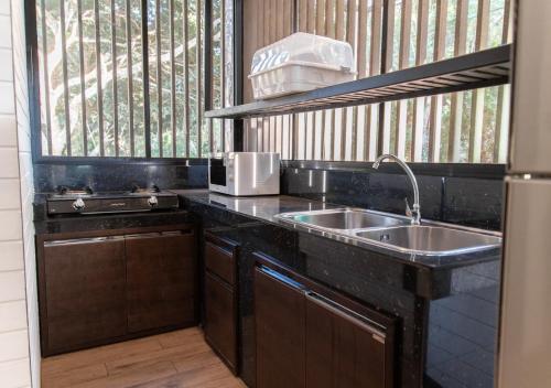 eine Küche mit einem Waschbecken und einem Fenster in der Unterkunft The Stream House in Ban Pok Nai