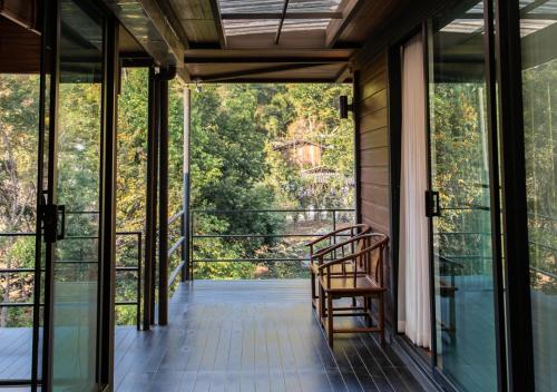 a room with glass doors and a chair on a balcony at The Stream House in Ban Pok Nai