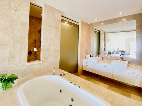 a large bathroom with two sinks and a tub at 237 Santai - Second floor studio by uHoliday in Casuarina